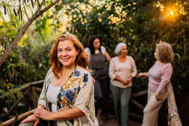 Grupo de mujeres adultas sonriendo y conversando al aire libre en un entorno natural durante el atardecer